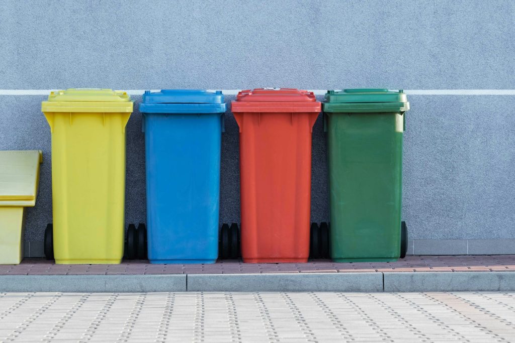 quatre poubelles de couleurs assorties à côté d'un mur gris